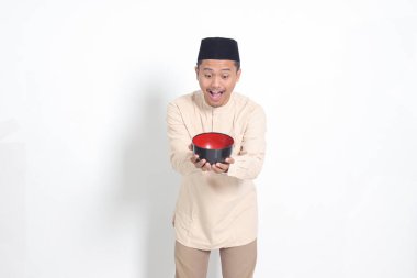 Koko gömlekli heyecanlı Asyalı Müslüman adamın portresi. Kafatası açık ve elinde boş bir tabak var. Gıda markası için kase şablonu. Beyaz arkaplanda izole