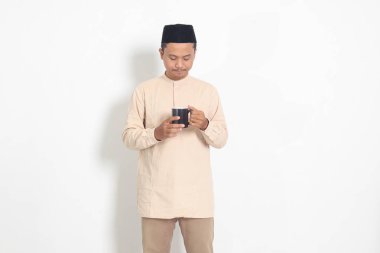 Koko tişörtlü çekici Asyalı Müslüman adamın portresi. Kaslı, fincanı tutan, içme suyu içen, oruç tuttuktan sonra susuzluğunu gideren. Beyaz arkaplanda izole edilmiş resim