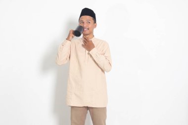 Koko tişörtlü çekici Asyalı Müslüman adamın portresi. Kaslı, fincanı tutan, içme suyu içen, oruç tuttuktan sonra susuzluğunu gideren. Beyaz arkaplanda izole edilmiş resim