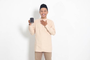 Koko tişörtlü çekici Asyalı Müslüman adamın portresi. Kaslı, fincanı tutan, içme suyu içen, oruç tuttuktan sonra susuzluğunu gideren. Beyaz arkaplanda izole edilmiş resim