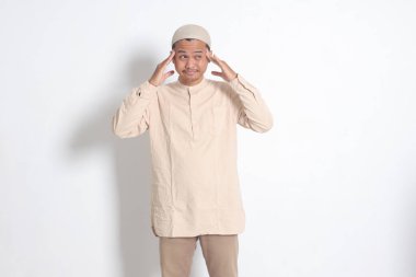 Beyaz gömlekli, migreni olan, şakağına dokunan Asyalı Müslüman adamın portresi. Baş ağrısı hastalığı konsepti. Beyaz arkaplanda izole edilmiş resim