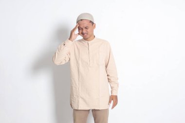 Beyaz gömlekli, migreni olan, şakağına dokunan Asyalı Müslüman adamın portresi. Baş ağrısı hastalığı konsepti. Beyaz arkaplanda izole edilmiş resim