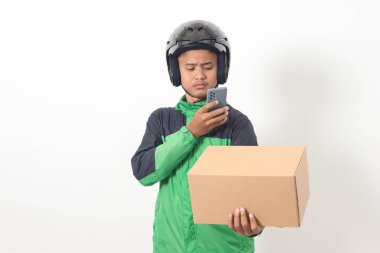 Yeşil ceket ve kask giyen Asyalı taksi şoförünün portresi bir kutu tutuyor ve paketi tarıyor veya yakalıyor. Beyaz arkaplanda izole edilmiş resim