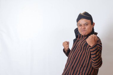 Beyaz şapkalı heyecanlı Asyalı adamın portresi yumruğunu kaldırıyor, bir yarışmayı kazandıktan sonra başarıyı kutluyor. Beyaz arkaplanda izole edilmiş resim