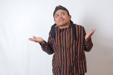 Kafası karışmış bir Asyalı adamın portresi, beyaz şapkalı, yanlamasına bakan, seçim yapan, iki obje arasından seçim yapan. Beyaz arkaplanda izole edilmiş resim