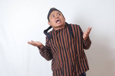 Kafası karışmış bir Asyalı adamın portresi, beyaz şapkalı, yanlamasına bakan, seçim yapan, iki obje arasından seçim yapan. Beyaz arkaplanda izole edilmiş resim