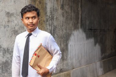 Beyaz gömlekli, içinde özgeçmişi olan kahverengi bir zarf taşıyan işsiz Asyalı bir adamın portresi. Personel alımı konsepti.