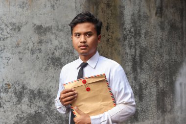 Beyaz gömlekli, içinde özgeçmişi olan kahverengi bir zarf taşıyan işsiz Asyalı bir adamın portresi. Personel alımı konsepti.