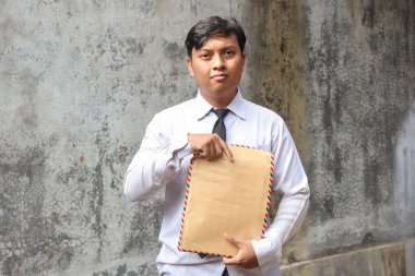 Beyaz gömlekli, içinde özgeçmişi olan kahverengi bir zarf taşıyan işsiz Asyalı bir adamın portresi. Personel alımı konsepti.