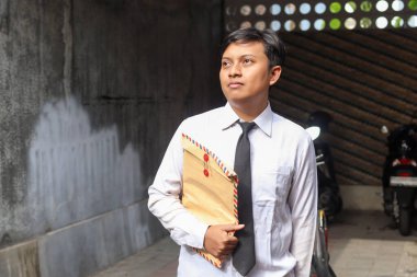 Beyaz gömlekli, içinde özgeçmişi olan kahverengi bir zarf taşıyan işsiz Asyalı bir adamın portresi. Personel alımı konsepti.