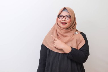 Tesettürlü neşeli Asyalı kadın portresi, ürünü gösteriyor, bir şeyi işaret ediyor ve gülümsüyor. Reklam konsepti. Beyaz arkaplanda izole edilmiş resim