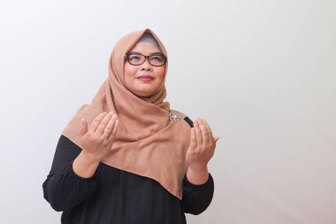 Tesettürlü ciddi bir Asyalı kadının portresi kaldırılmış ellerle Tanrı 'ya dua ediyor. Beyaz arkaplanda izole edilmiş resim