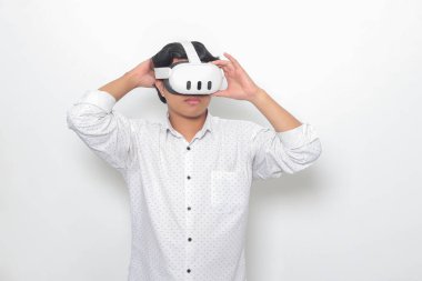 Sanal gerçeklik VR cihazı kullanan Asyalı bir adamın portresi, büyüleyici bir teknoloji deneyimliyor. Beyaz arkaplanda izole edilmiş resim