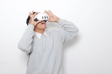 Sanal gerçeklik VR cihazı kullanan Asyalı bir adamın portresi, büyüleyici bir teknoloji deneyimliyor. Beyaz arkaplanda izole edilmiş resim