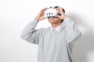 Sanal gerçeklik VR cihazı kullanan Asyalı bir adamın portresi, büyüleyici bir teknoloji deneyimliyor. Beyaz arkaplanda izole edilmiş resim