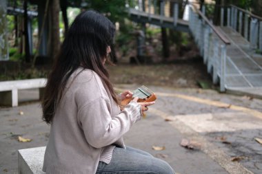 Asyalı bir kadın güneşli bir günde yeşil bir parkta kalimba çalar. Sakin melodiler ve gür yapraklar huzur verici ve rahatlatıcı bir sahne yaratır.