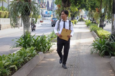Beyaz gömlekli Asyalı bir iş arayanın portresi. İçinde özgeçmişi olan kahverengi bir zarfı tutarken iş arıyor. Şehir caddesinde aceleyle yürüyor. Personel alımı konsepti