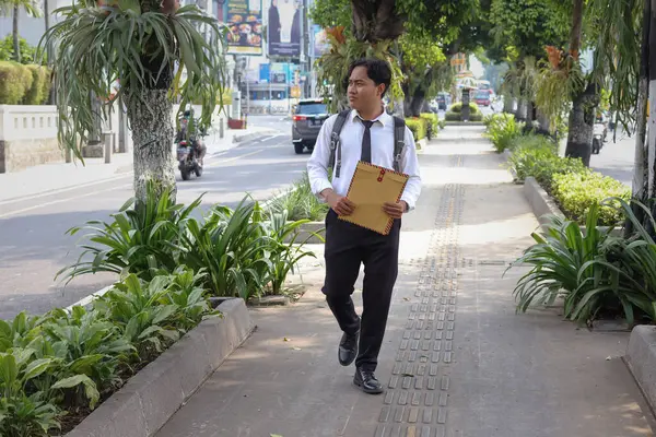 Beyaz gömlekli Asyalı bir iş arayanın portresi. İçinde özgeçmişi olan kahverengi bir zarfı tutarken iş arıyor. Şehir caddesinde aceleyle yürüyor. Personel alımı konsepti