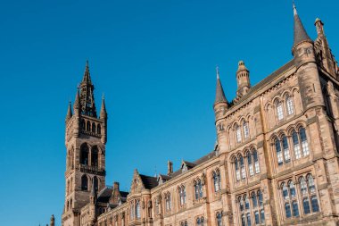 Glasgow İskoçya: 8 Ocak 2025: Glasgow Üniversitesi Gilmorehill. Gündüz vakti Glasgow 'da açık mavi gökyüzü altında bir üniversite binasının tarihi mimarisi