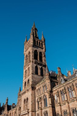 Glasgow İskoçya: 8 Ocak 2025: Glasgow Üniversitesi Gilmorehill. Gündüz vakti Glasgow 'da açık mavi gökyüzü altında bir üniversite binasının tarihi mimarisi