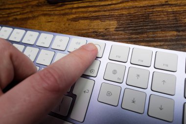 Newcastle UK: 28 Aralık 2023: M1 iMac 'ten alınmış dokunmatik kimlikli mor bir Apple Klavyesi kullanan bir el