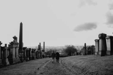 Glasgow İskoçya: 12 Şubat 2024: Glasgow Mezarlığı Endüstriyel görünümlü iki kişi kameradan uzaklaşıyor