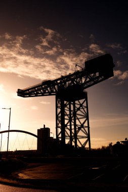 Glasgow İskoçya: 13 Şubat 2024 Finnieston Crane ve Clyde Arc güneşli bir altın saat siluetinde. Nehir kıyısında Clyde