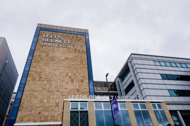 Leeds England: 3 Haziran 2024: Leeds Beckett Üniversitesi dış kampüsü. Dıştan geniş açı, ağaçlar ve üniforma işareti, mor bayrak.