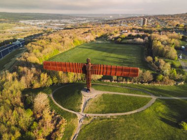Gateshead UK: 13 Nisan 2025: Sanatçı Antony Gormley 'nin Kuzey Meleği heykelini aydınlatan şafak ışığı Gateshead' de canlı renklerde insansız hava aracı pov