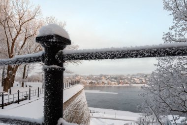 Narva (Estonya - Rusya) sınır nehri üzerinde kalın don kaplı metal bir çitin ardında güzel bir kış manzarası. Bulutlu bulutlu mavi gökyüzü ve soğuk bir Ocak gününün sonunda hilal ay.
