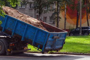 Mavi bir çöp kamyonu Estonya 'nın Narva kentindeki yüksek binaların avlusuna kum boşaltıyor. Bu güneşli eylül sahnesinde kentsel yapı ve yenileme çalışmaları resmediliyor.