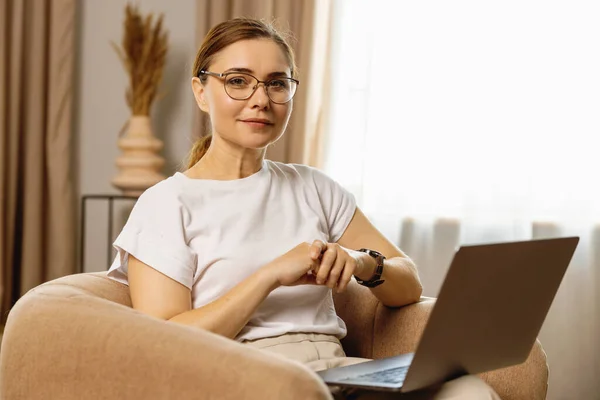 Portrait Middle Aged Woman Eyeglasses Sitting Armchair Laptop Her Knee Stock Photo