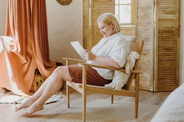 Junge Blonde Frau Sitzt Hause Auf Stuhl Mit Tablet Stockbild