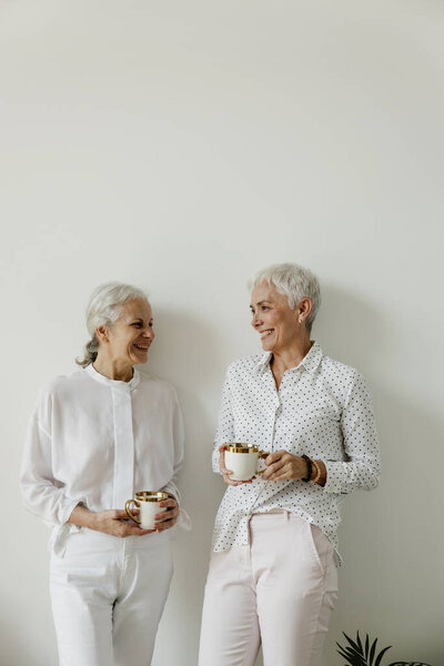 Senior Females Drinking Coffee Laughing White Wall Background Copy Space Royalty Free Stock Images