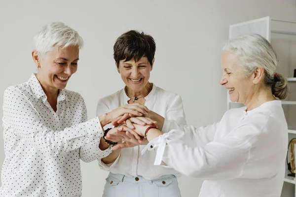 Três Mulheres Maduras Elegantes Confiantes Empilhando Mãos Sorrindo Imagem De Stock