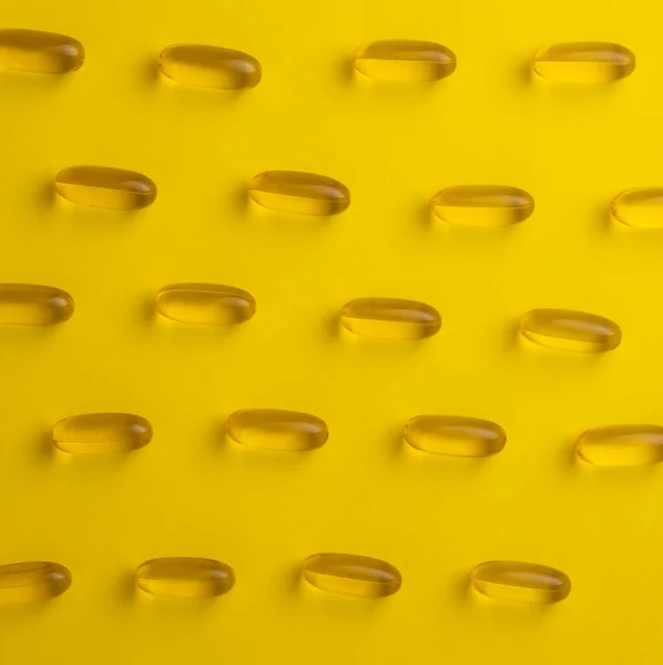 Fish oil omega 3 gel capsules on yellow background and arranged in rows. High quality photo