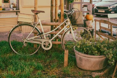 Siyah lastikli beyaz bir bisiklet bir binanın önündeki çimlerin üzerinde park edilmiştir. Tekerlekler tahtadan yapılmış ve binanın üzerinde bir pencere var.