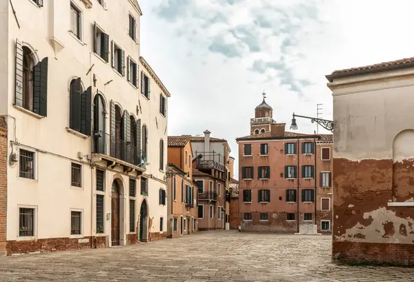 Benzersiz cepheli binalar şehrin parke taşı sokağında bulutlu bir gökyüzünün altında. Pencereler ve aksesuarlar her evi süsler, gezginler için resim gibi bir sahne yaratır.