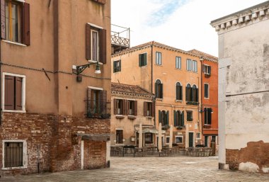 Benzersiz cepheli binalar şehrin parke taşı sokağında bulutlu bir gökyüzünün altında. Pencereler ve aksesuarlar her evi süsler, gezginler için resim gibi bir sahne yaratır.