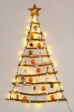 Christmas creative decoration - homemade wooden hanging christmas tree on the wall clipart