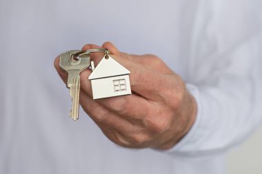 Man's hand holding a house key. Concept of buying a new house or home.
