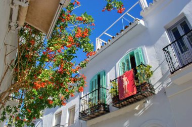Street of famous white spanish village Frigiliana with symbol of religious patron San Sebastian - Andalusia, Spain