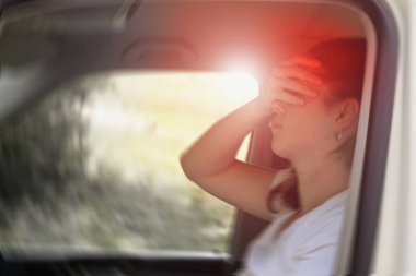 Blured photo of a woman sitting in the car suffering from vertigo or dizziness or other health problem of brain or inner ear. clipart