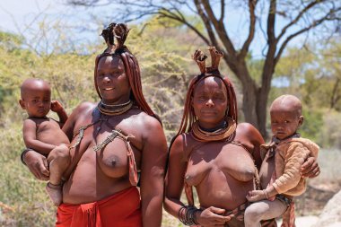 Kunene Bölgesi, Namibya, Afrika - 20.11.2023: Himba kabilesi yerli kadınları geleneksel giysi ve mücevherler giyiyorlar. Anneler ve bebekleri .