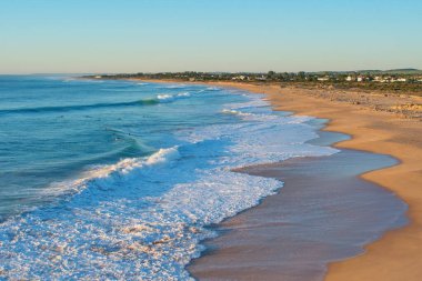 Cape Trafalgar yakınlarındaki sahil, Costa de la Luz, İspanya, Endülüs. Dalgalar ve sörfçülerle gün batımı sahnesi.