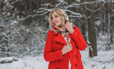 Etik eşarplı ve kırmızı ceketli bir bayan, kış tatilleri, açık havada ormanda bir kadın. Noel zamanı kavramı