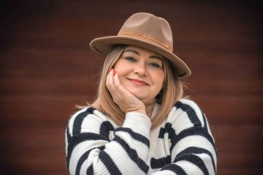 Women psychology. Portrait of mature plus size lady in beige hat and striped sweater