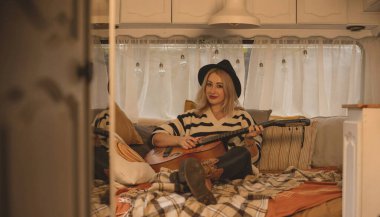 Hippie Boho girl with guitar in trailer, rest relaxing vibe