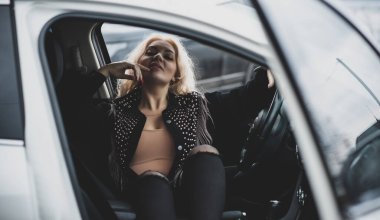 European sexy elegant woman in car, lady driving automobile, outdoors portrait. Woman on road, trip on beautiful day. Concept of women and auto