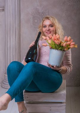 Nice happy woman celebrate with bottle of Champaign and flowers. Happy mood